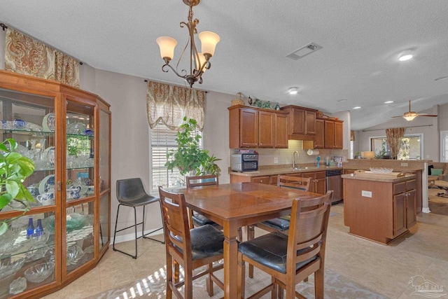 dining room with ceiling fan with notable chandelier, vaulted ceiling, sink, and a textured ceiling