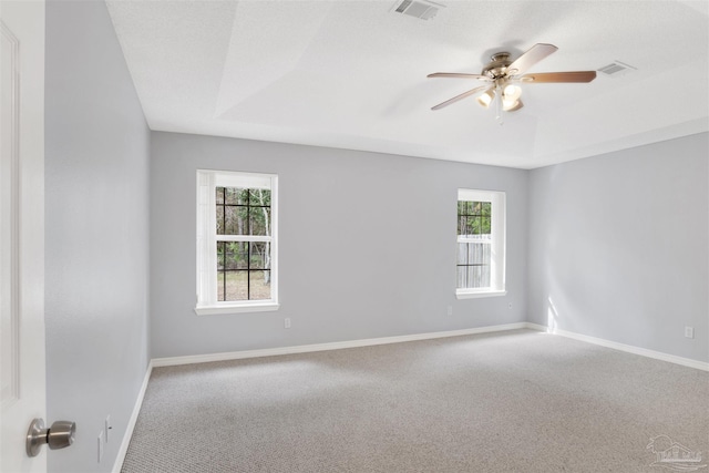 carpeted empty room featuring ceiling fan, a tray ceiling, and a textured ceiling