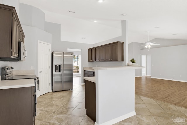 kitchen with dark brown cabinetry, vaulted ceiling, light tile patterned floors, ceiling fan, and stainless steel appliances