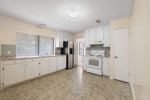 kitchen with white appliances, under cabinet range hood, white cabinets, and a sink