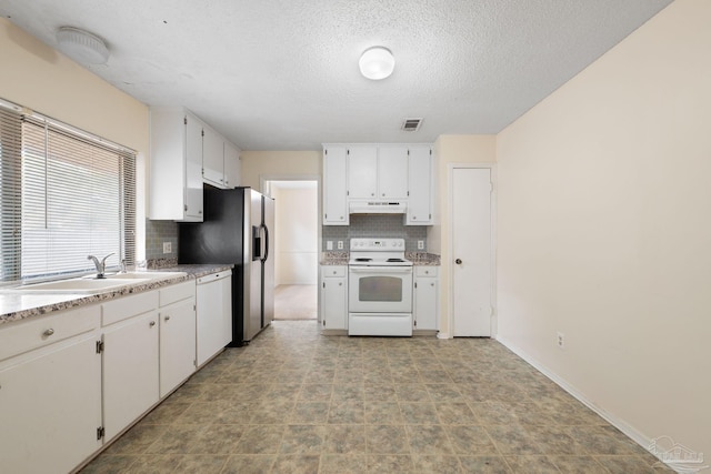 kitchen featuring white appliances, tasteful backsplash, white cabinets, under cabinet range hood, and a sink