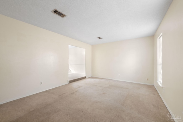 unfurnished room featuring light carpet, a textured ceiling, visible vents, and a healthy amount of sunlight