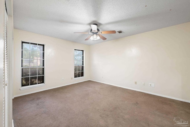 carpeted spare room with a textured ceiling, a ceiling fan, visible vents, and baseboards