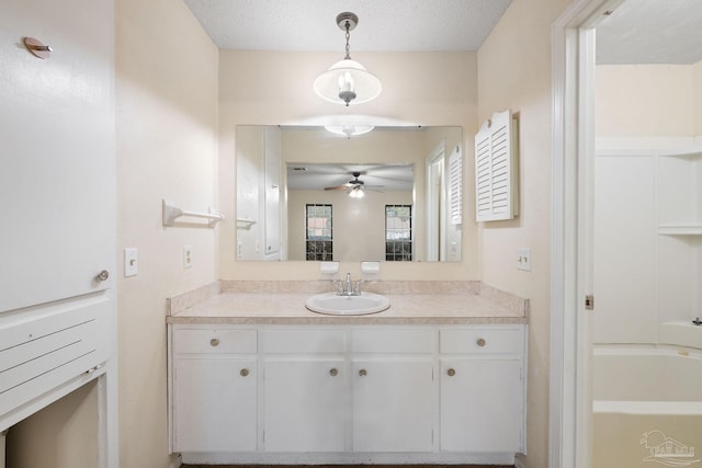 bathroom featuring a textured ceiling, a ceiling fan, a bath, and vanity