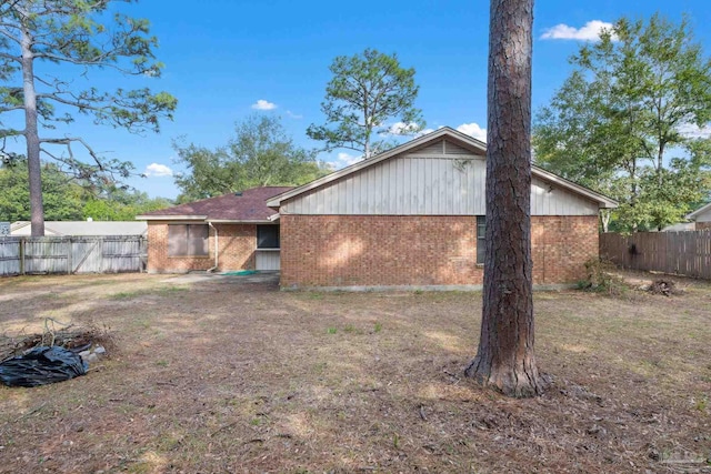 rear view of property featuring brick siding and fence