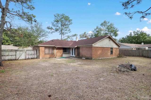 rear view of property with a fenced backyard, a chimney, and brick siding