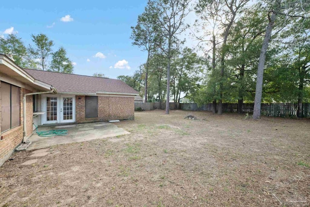 view of yard featuring french doors, a patio area, and fence