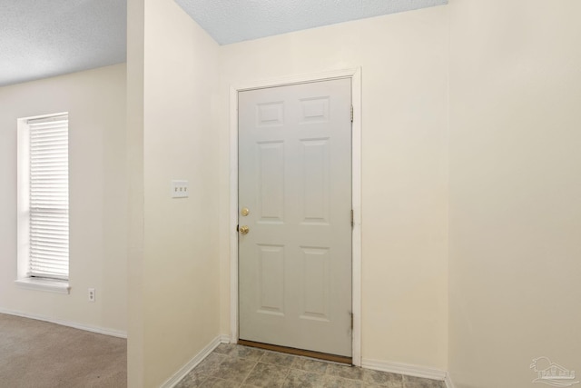 doorway to outside featuring a textured ceiling and baseboards