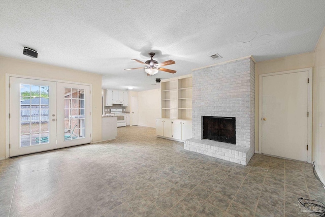 unfurnished living room with built in shelves, french doors, visible vents, a brick fireplace, and a textured ceiling