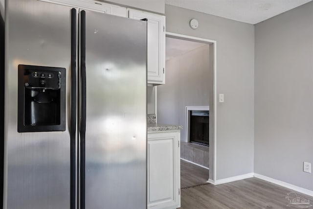 2811 Langley Ave Unit 221, Pensacola, FL 32504 - kitchen with stainless steel fridge with ice dispenser, wood finished floors, white cabinetry, and baseboards