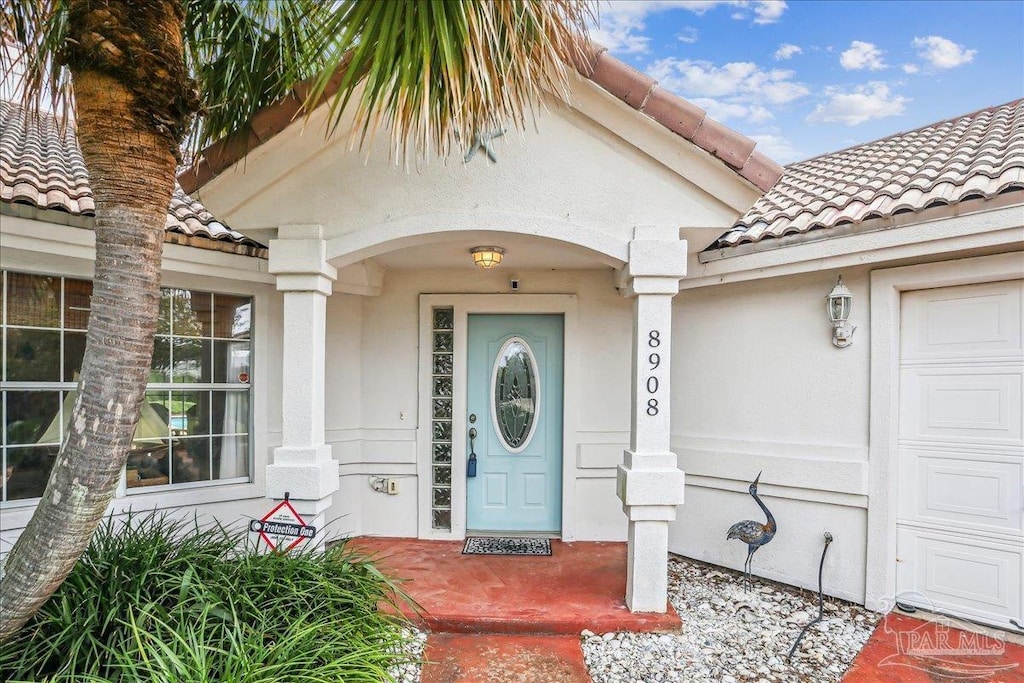 8908 Cutter Ct, Navarre, FL 32566 - property entrance with a tile roof, stucco siding, and covered porch