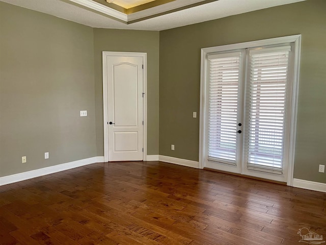 spare room with baseboards and dark wood-style flooring