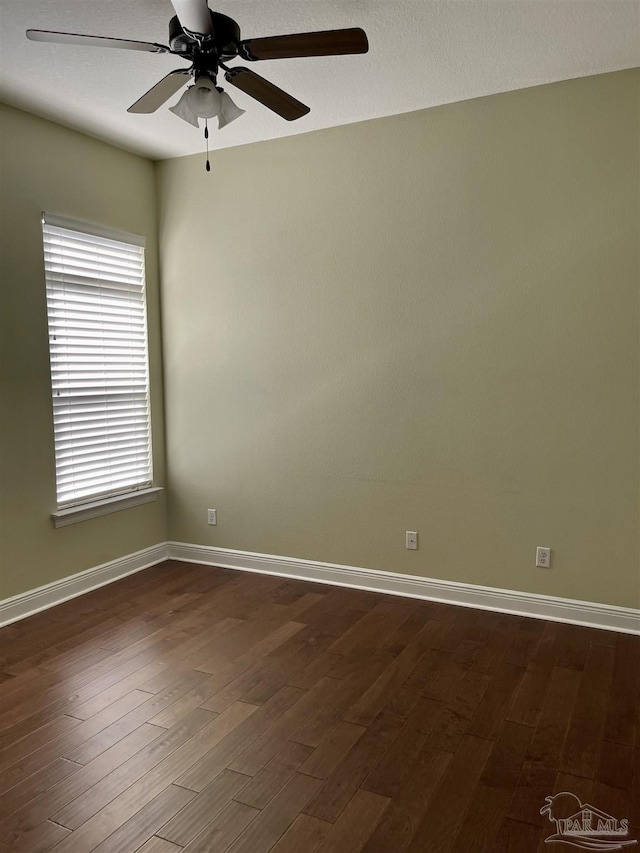 unfurnished room with dark wood-style floors, a ceiling fan, and baseboards