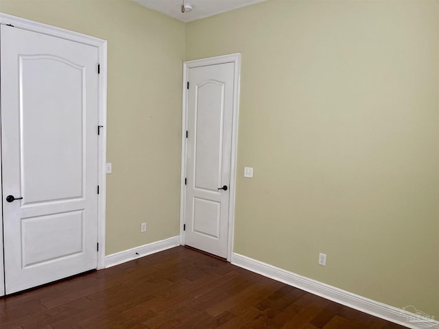 unfurnished bedroom featuring baseboards and dark wood-type flooring