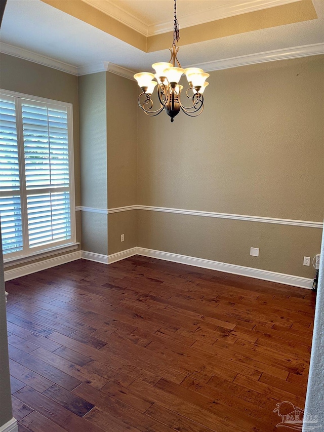 empty room with dark wood-style floors, baseboards, ornamental molding, and a notable chandelier