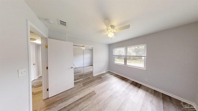 unfurnished bedroom with ceiling fan, light hardwood / wood-style flooring, and a closet