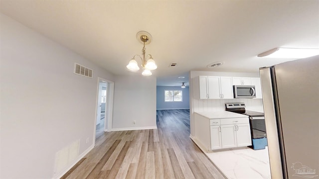 kitchen with tasteful backsplash, white cabinets, stainless steel appliances, and decorative light fixtures