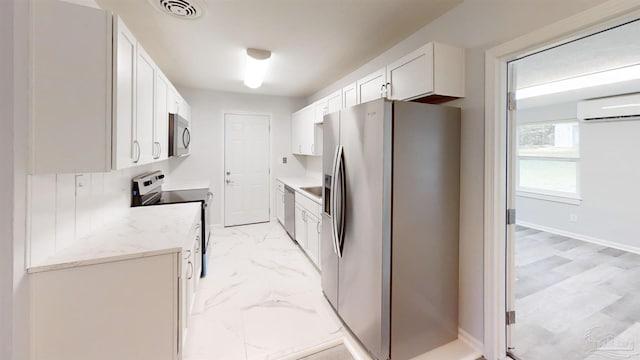 kitchen featuring a wall mounted air conditioner, white cabinets, sink, light stone counters, and stainless steel appliances