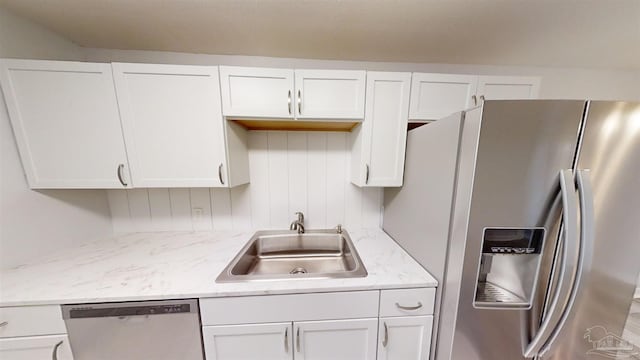 kitchen with white cabinets, sink, light stone countertops, and stainless steel appliances