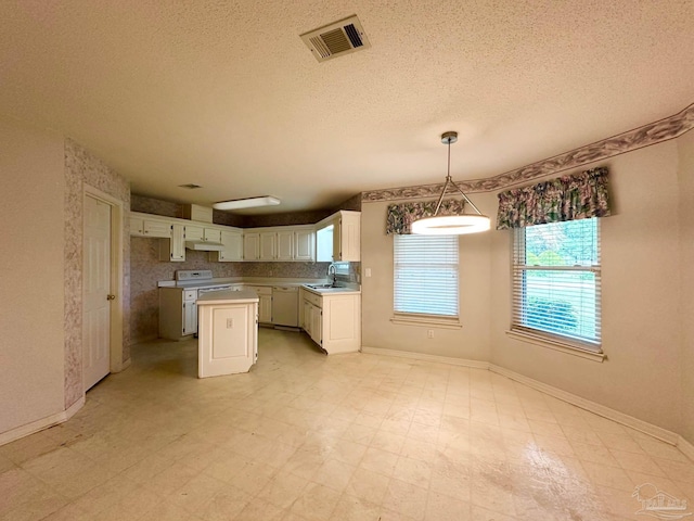 5473 Timber Creek Cir, Pace, FL 32571 - kitchen featuring a center island, under cabinet range hood, white cabinetry, light flooring, and a textured ceiling