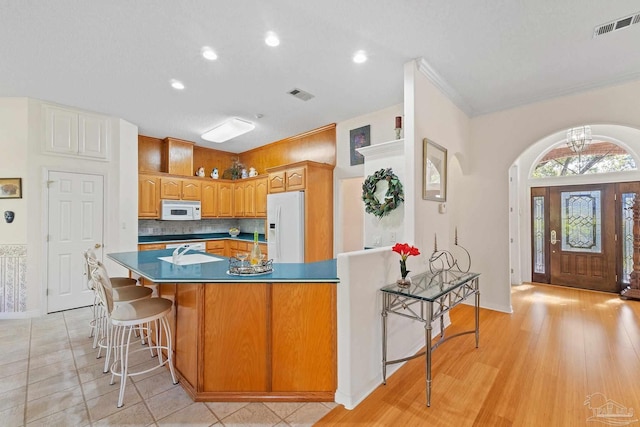 kitchen featuring light hardwood / wood-style flooring, backsplash, crown molding, white appliances, and a kitchen island