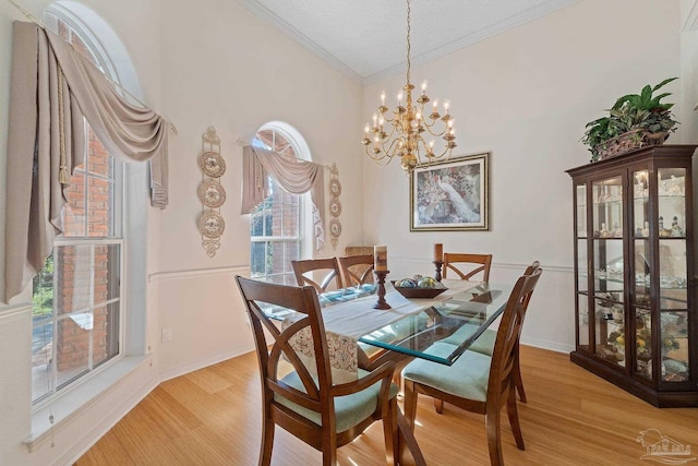 dining space featuring crown molding, a chandelier, a textured ceiling, and light wood-type flooring