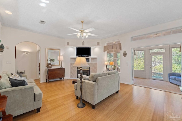 living room with a textured ceiling, light hardwood / wood-style floors, ceiling fan, and crown molding