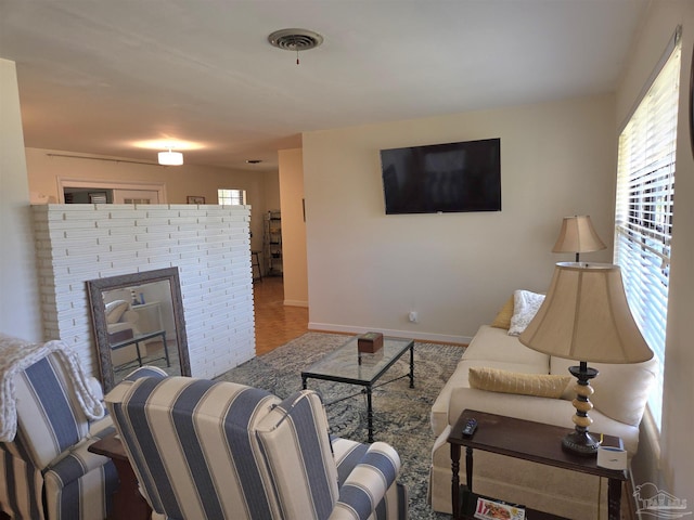 living area featuring a brick fireplace, visible vents, plenty of natural light, and baseboards