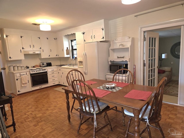 kitchen featuring white fridge with ice dispenser, a sink, white cabinets, and under cabinet range hood