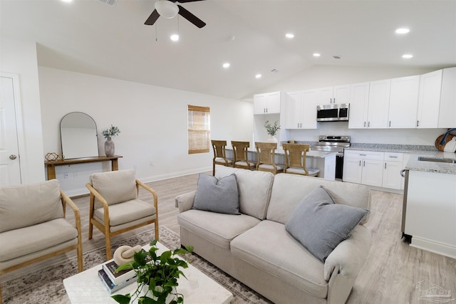 living room featuring sink, vaulted ceiling, ceiling fan, and light wood-type flooring