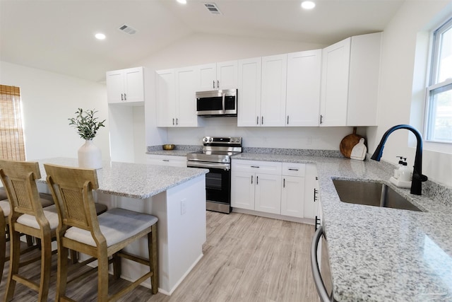 kitchen with stainless steel appliances, sink, a breakfast bar area, and white cabinets