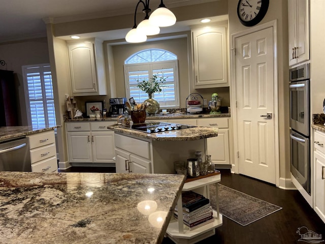 kitchen featuring appliances with stainless steel finishes, hanging light fixtures, light stone counters, ornamental molding, and white cabinets