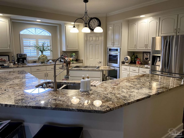 kitchen with appliances with stainless steel finishes, white cabinetry, a spacious island, decorative light fixtures, and dark stone counters