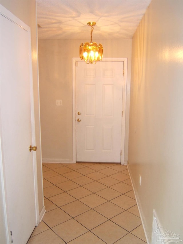 corridor with light tile patterned floors and a chandelier