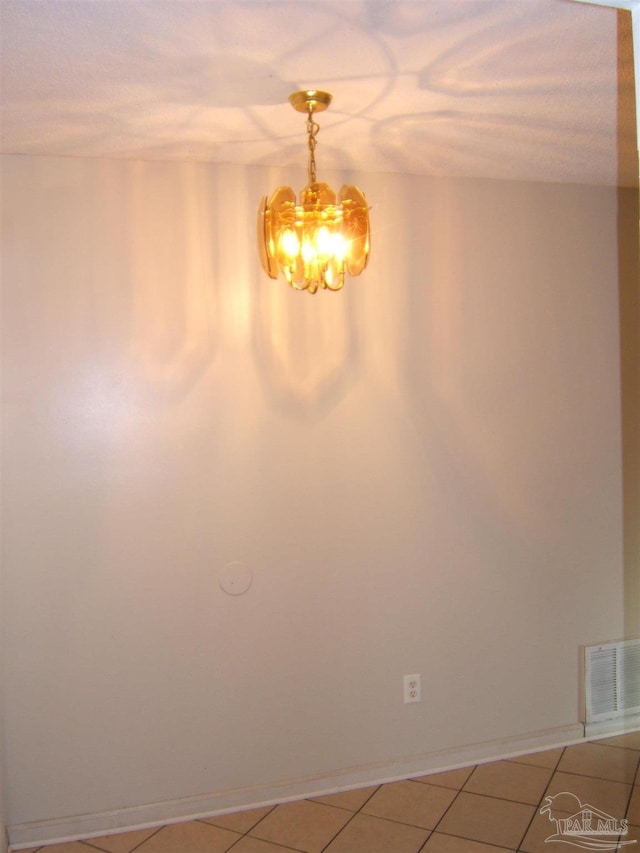 spare room featuring an inviting chandelier and tile patterned floors