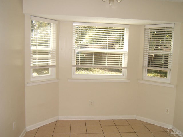 unfurnished room with light tile patterned floors and a wealth of natural light