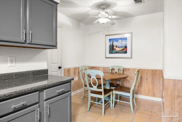 tiled dining area with wooden walls, ceiling fan, and a textured ceiling