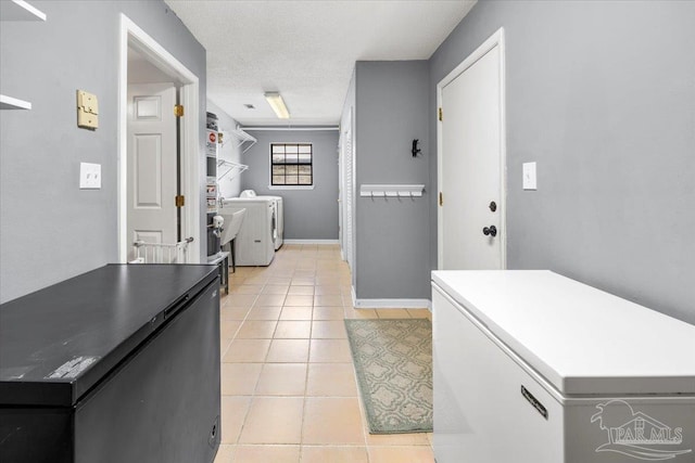 interior space with white fridge, a textured ceiling, light tile patterned flooring, and separate washer and dryer