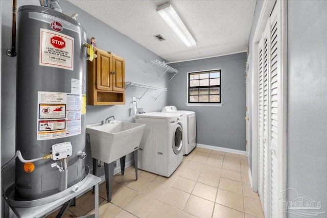 laundry room with light tile patterned floors, water heater, washer and dryer, and a textured ceiling