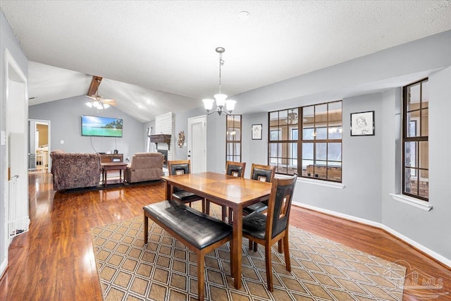 dining area featuring a textured ceiling, ceiling fan with notable chandelier, lofted ceiling with beams, and hardwood / wood-style floors