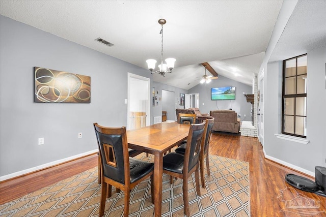 dining space with vaulted ceiling with beams, hardwood / wood-style flooring, and ceiling fan with notable chandelier