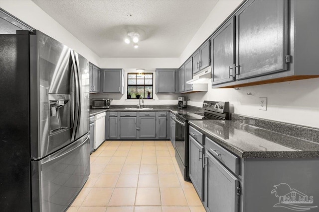 kitchen featuring a textured ceiling, gray cabinetry, sink, and stainless steel appliances