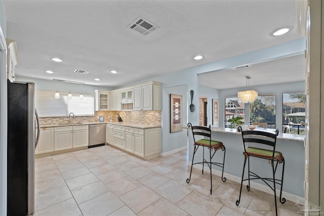 kitchen featuring tasteful backsplash, light stone counters, decorative light fixtures, and appliances with stainless steel finishes