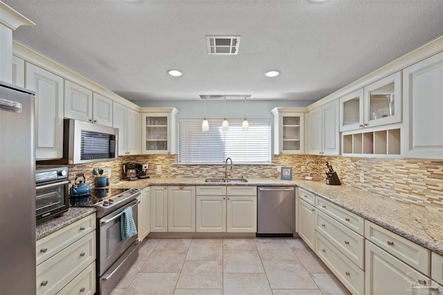 kitchen featuring sink, light tile patterned floors, tasteful backsplash, decorative light fixtures, and stainless steel appliances