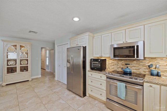 kitchen featuring decorative backsplash, light tile patterned floors, light stone countertops, and appliances with stainless steel finishes