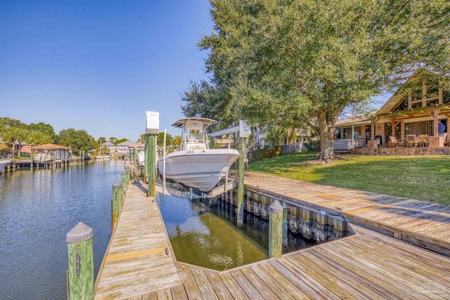 view of dock with a lawn and a water view