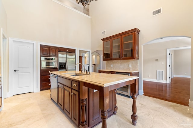 3869 Paradise Bay Dr, Gulf Breeze, FL 32563 - kitchen with arched walkways, a sink, a towering ceiling, appliances with stainless steel finishes, and beverage cooler