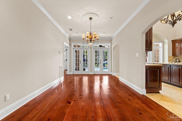 3869 Paradise Bay Dr, Gulf Breeze, FL 32563 - unfurnished dining area featuring a chandelier, arched walkways, light wood-style floors, baseboards, and ornamental molding