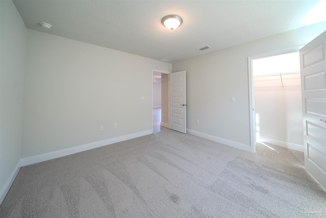 unfurnished bedroom with light carpet, a walk in closet, and a closet