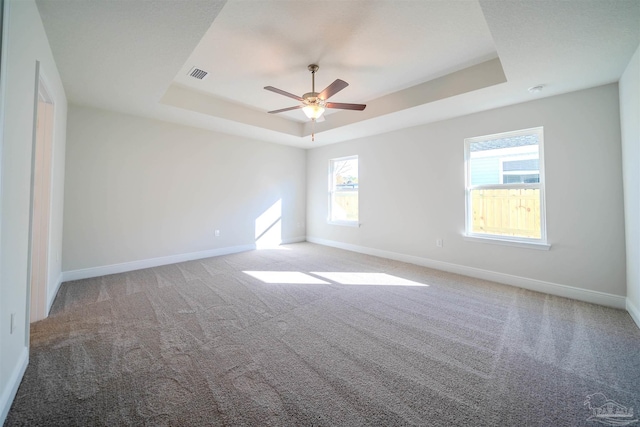 carpeted spare room featuring a raised ceiling and ceiling fan